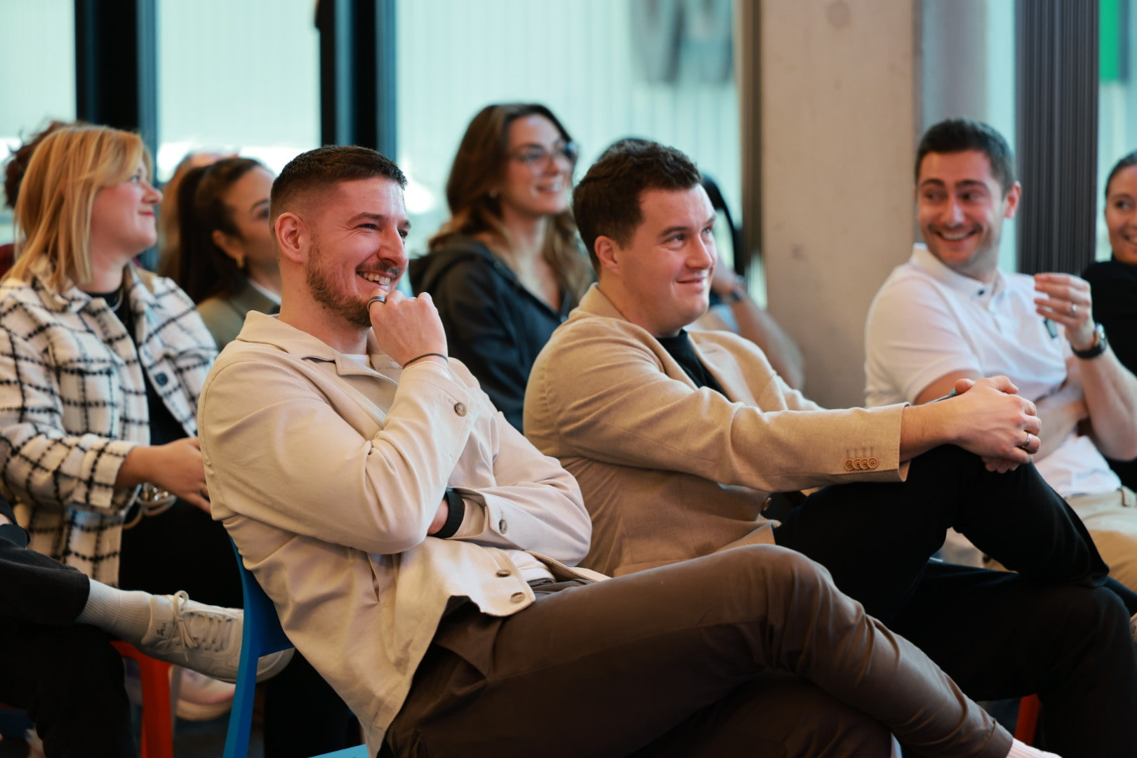 Client team members seated in daylight, leaning in and smiling during an AI Operator session in Munich.