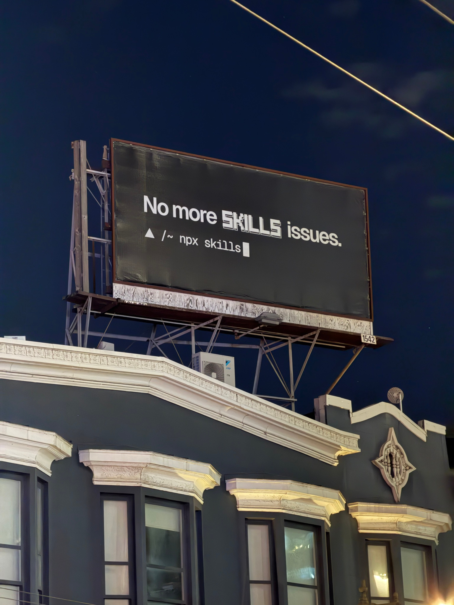 A billboard above a San Francisco building at night reading No more SKILLS issues, with the command npx skills beneath it.