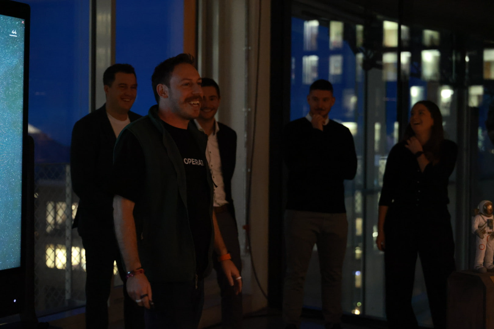 Tim Cakir laughing with a group of client team members in the evening at a kick-off in Munich, city lights behind them.